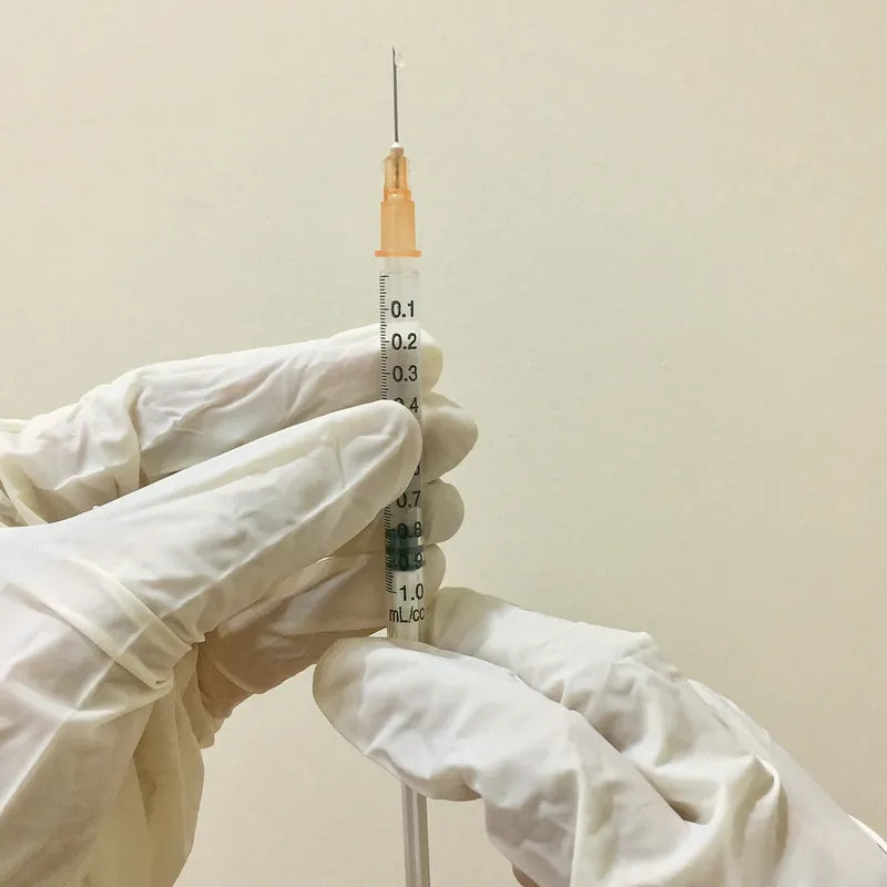 Manos con guantes médicos preparando un tratamiento